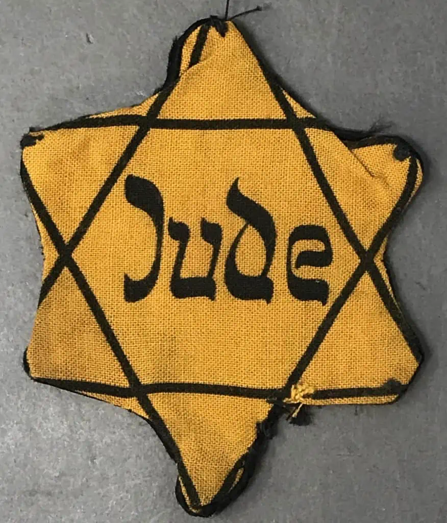 Rare worn Star of David badge with 'Jude' inscription, part of a historical display on the Holocaust