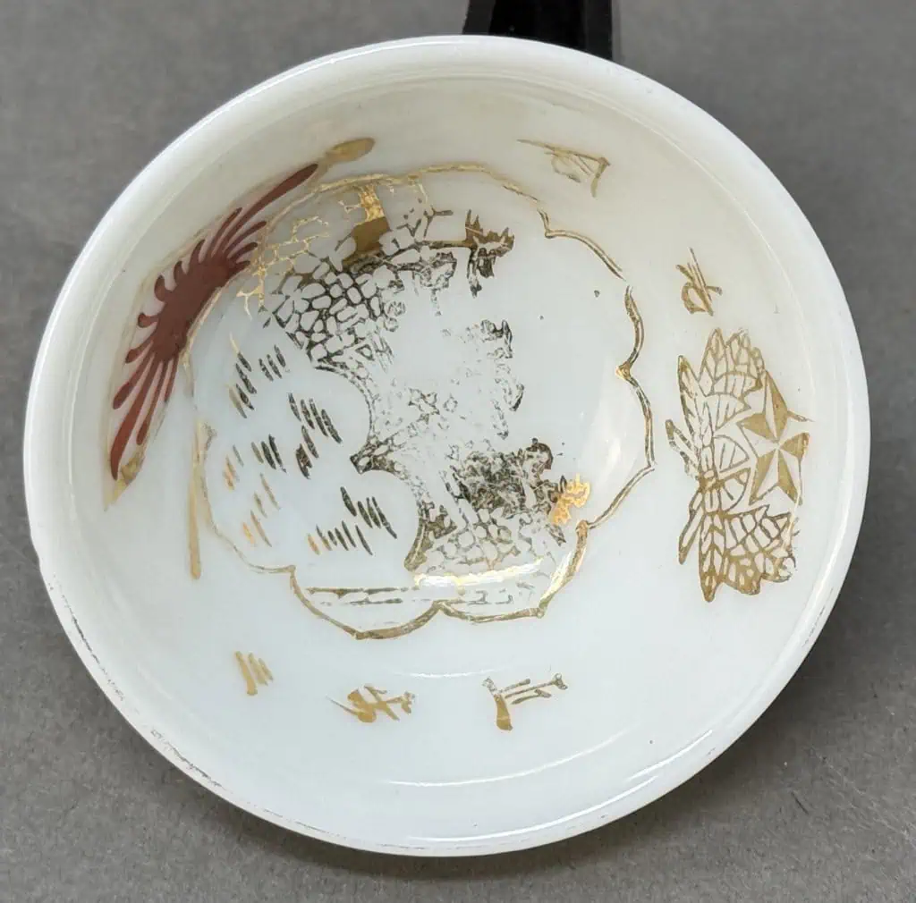 Vintage porcelain dish with gold and red decorative patterns, worn and chipped.