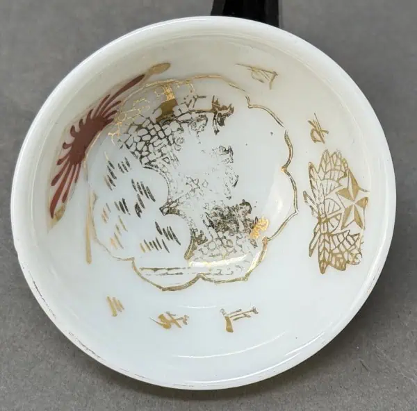 Vintage porcelain dish with gold and red decorative patterns, worn and chipped.