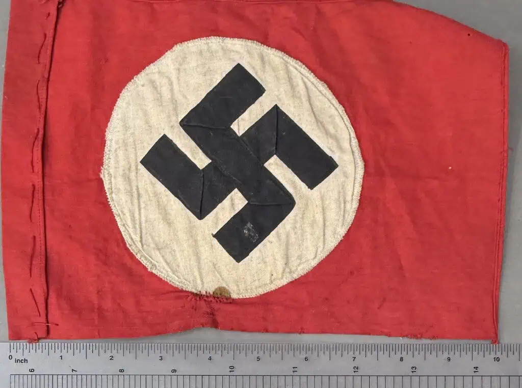 Historic Nazi swastika flag on red fabric with white circle background.