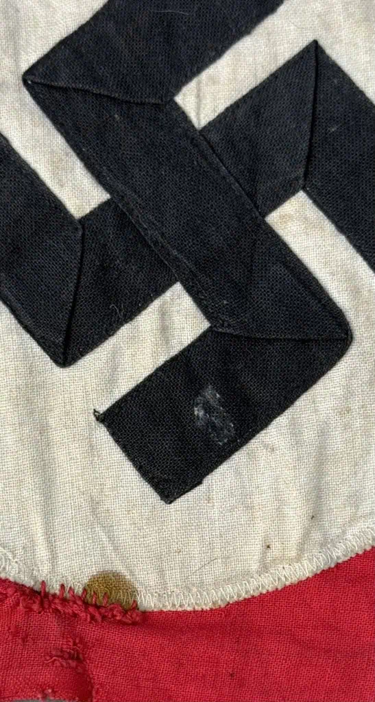 Black leather belt with a metal buckle, laid out on a fabric surface.