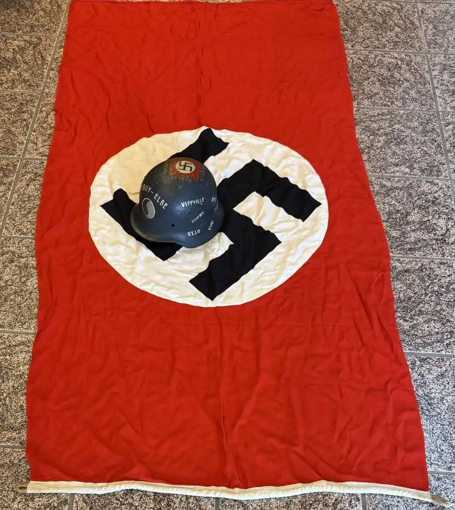 Nazi flag with swastika symbol on a red background, displayed on the floor.
