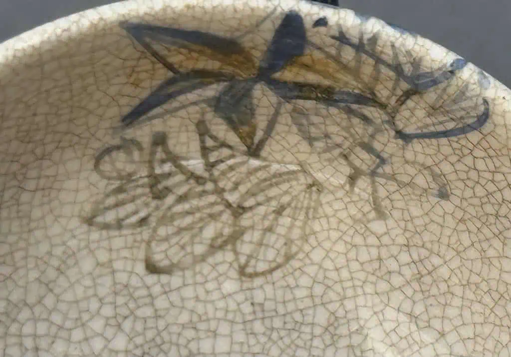 Antique ceramic plate with a crackled glaze and faded floral design.